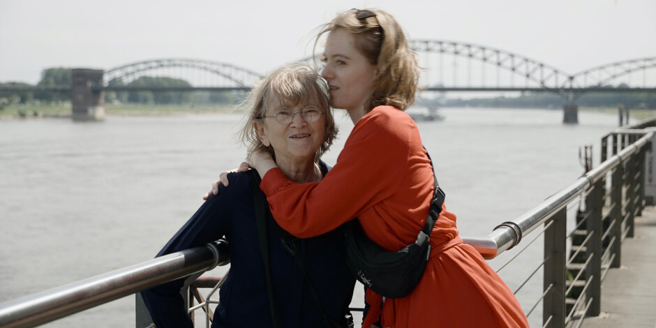 Anna und ihre Oma umarmen sich am Rheinufer